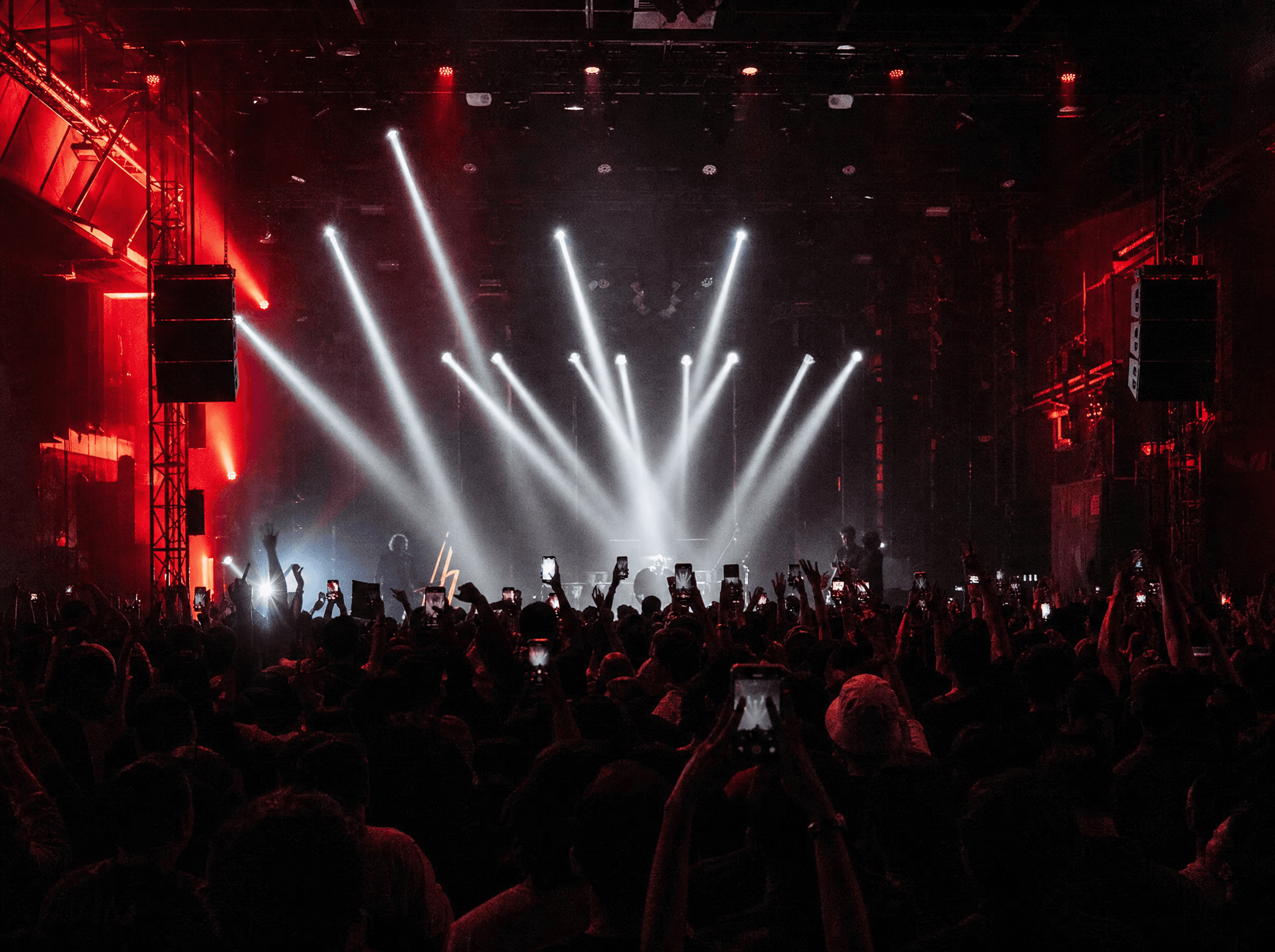 Crowd recording a live event under red stage lights
